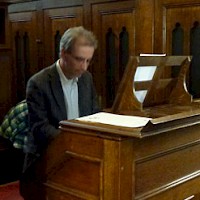 Marcel Verheggen tijdens orgelconcert achter de weer in het midden opgestelde speeltafel..
