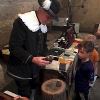 Muntmeester Jan Jansen laat kinderen hun eigen munt maken.